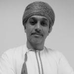 A man in traditional attire looks directly at the camera