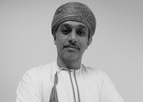 A man in traditional attire looks directly at the camera