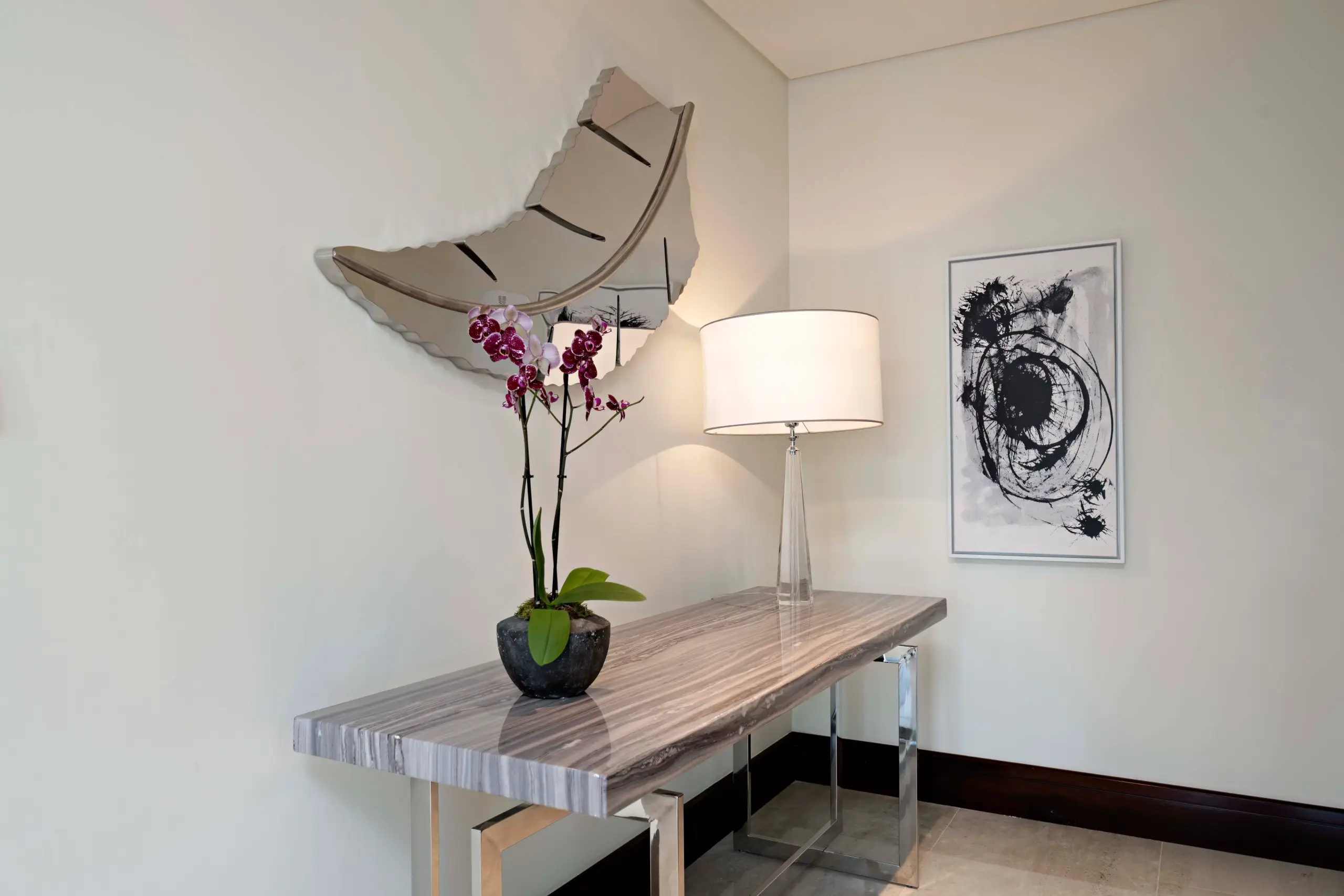 A hallway console table with orchid and art.