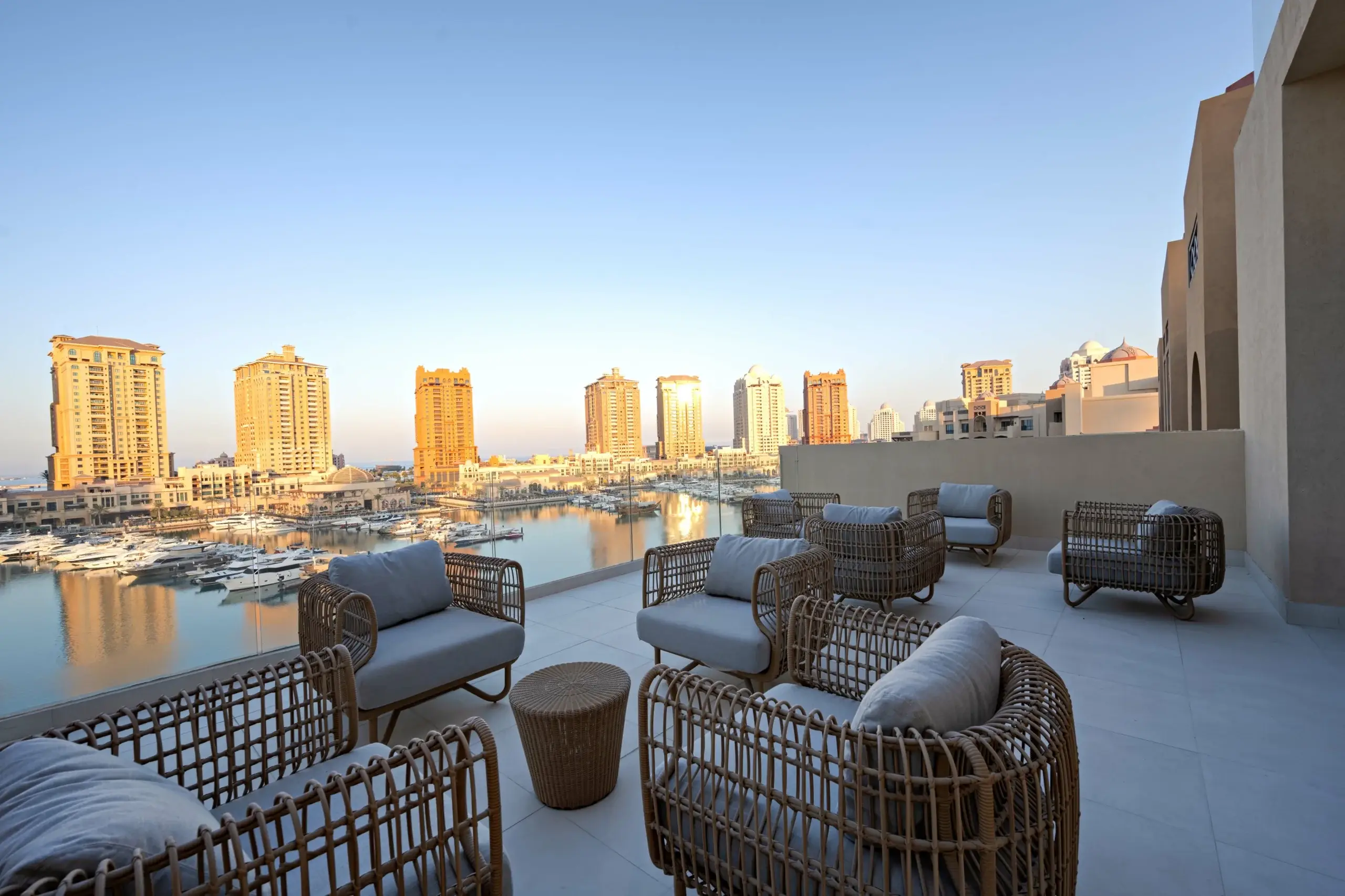 A rooftop terrace overlooks a marina and city.