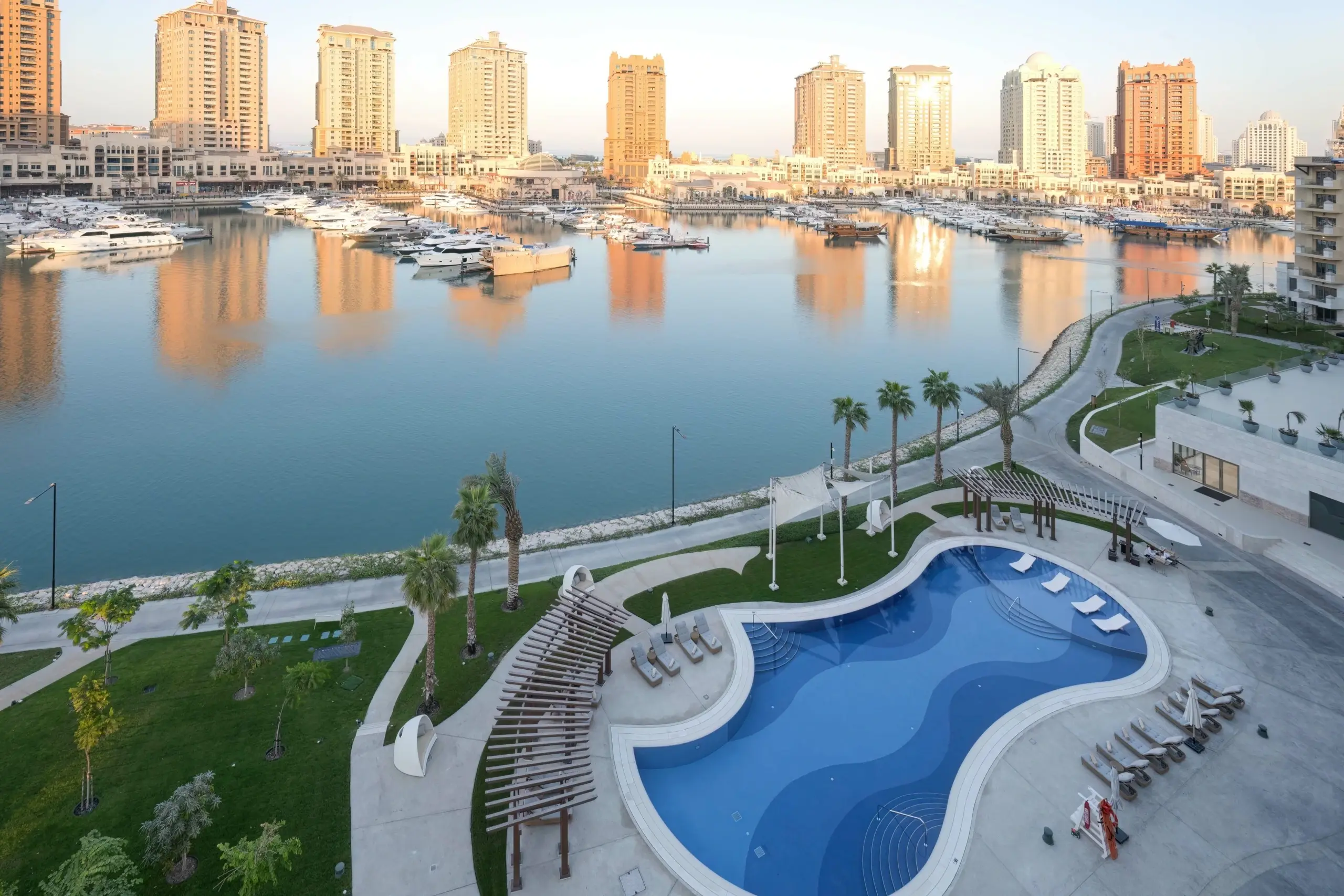 A luxurious pool by a marina and city skyline.