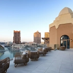 A rooftop terrace overlooks a marina and buildings.
