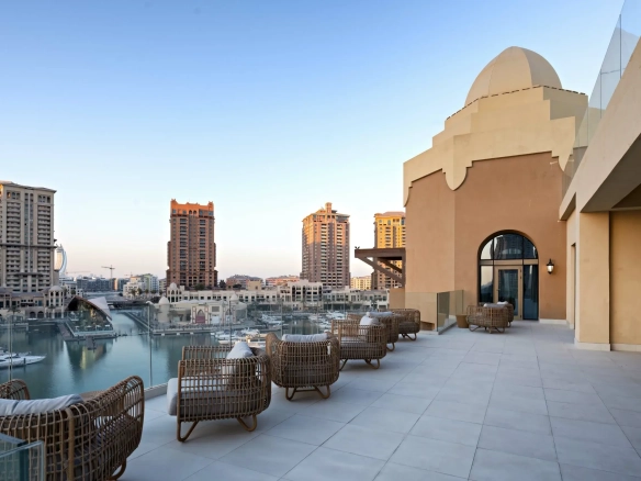 A rooftop terrace overlooks a marina and buildings.