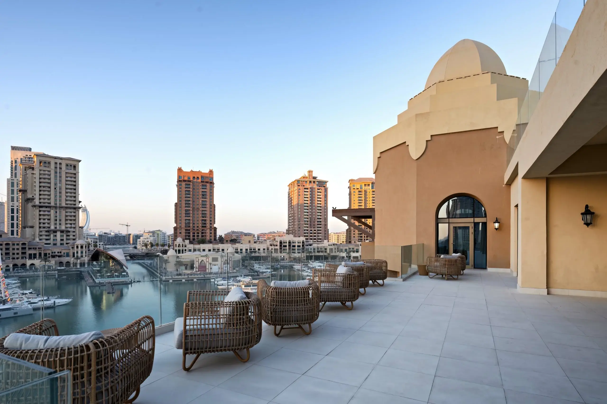 MARSA_6910-022-scaled-1 A rooftop terrace overlooks a marina and buildings.