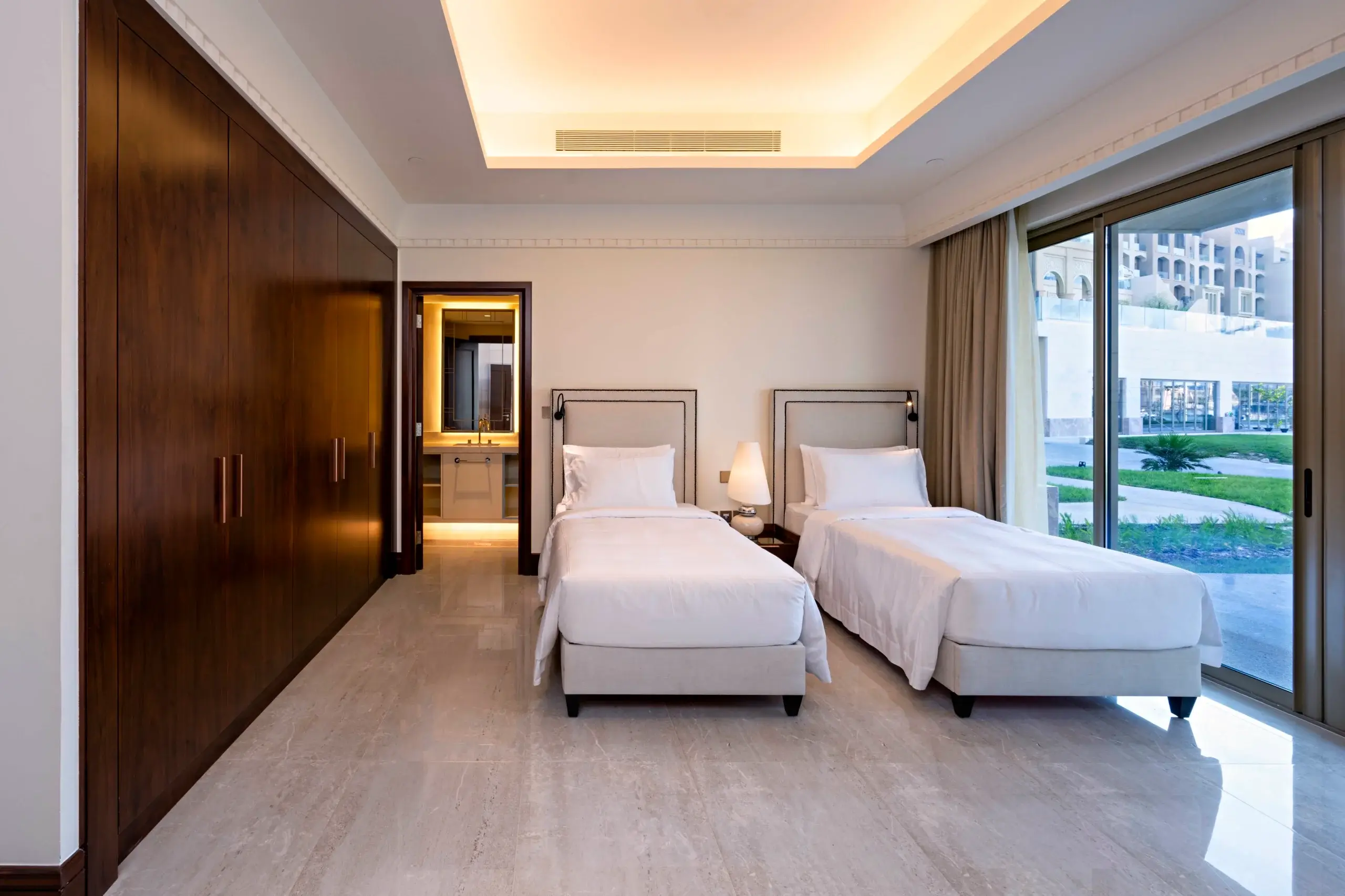 A twin bedroom with wooden wardrobes and a balcony