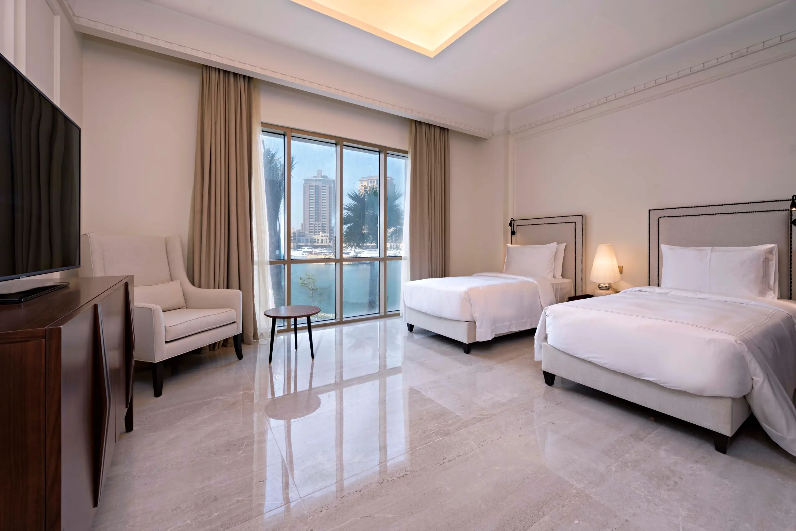 A hotel room with two beds, a sitting area, and a view