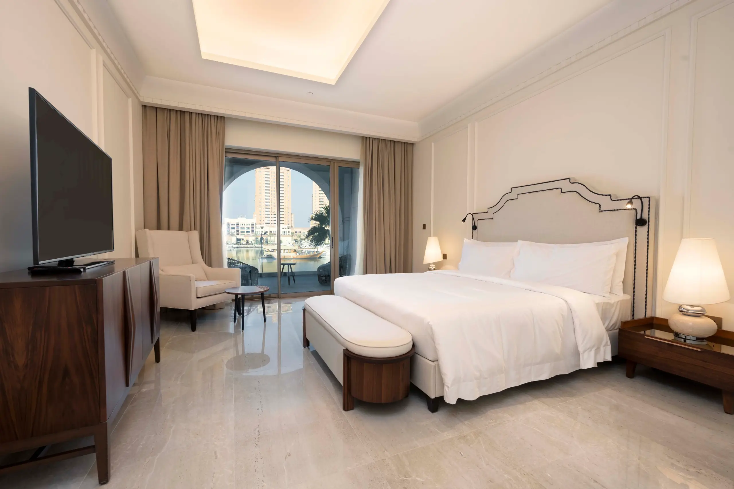 A hotel bedroom with a bed, TV, and balcony.