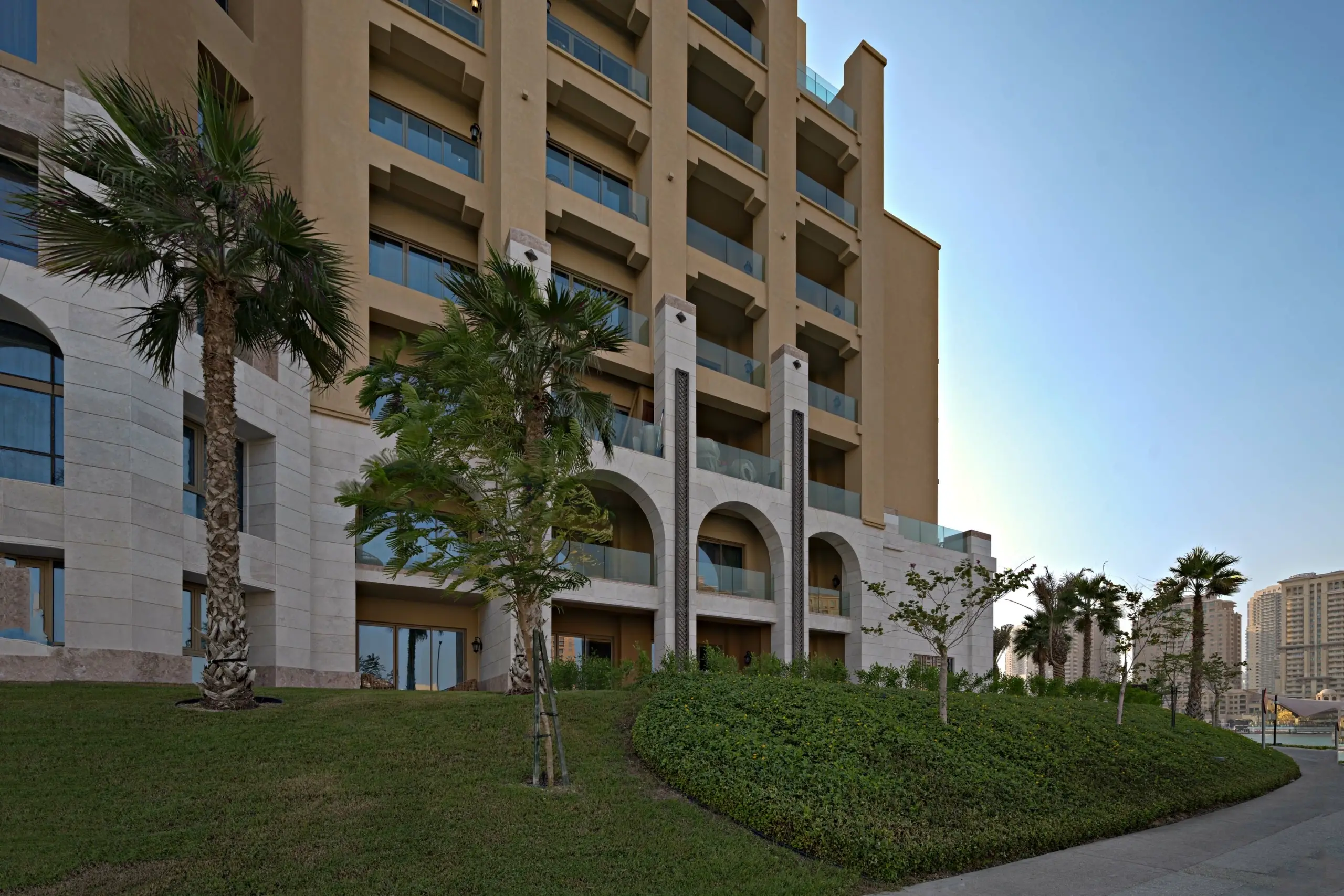 A multi-story building with balconies and palm trees