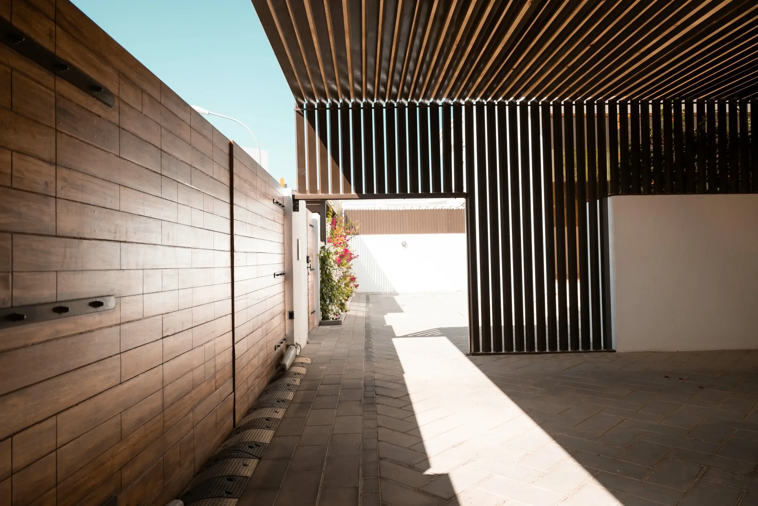 Pathway with wood wall and slatted pergola.