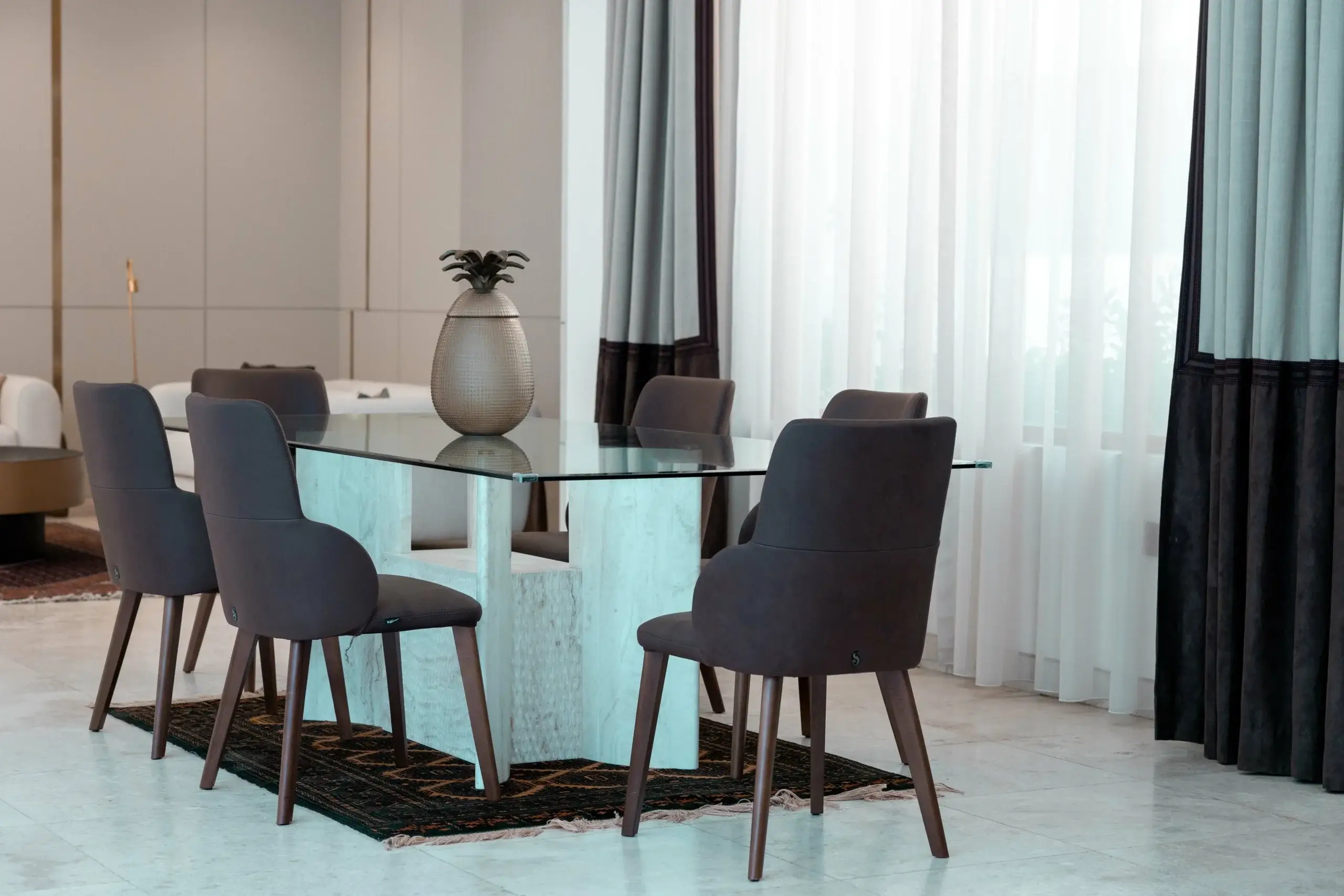 A dining room with a glass table and dark chairs
