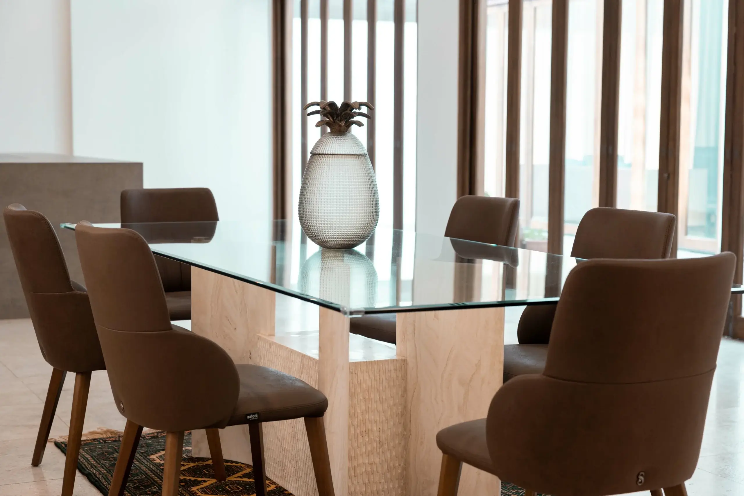 Dining room with glass table and brown chairs.