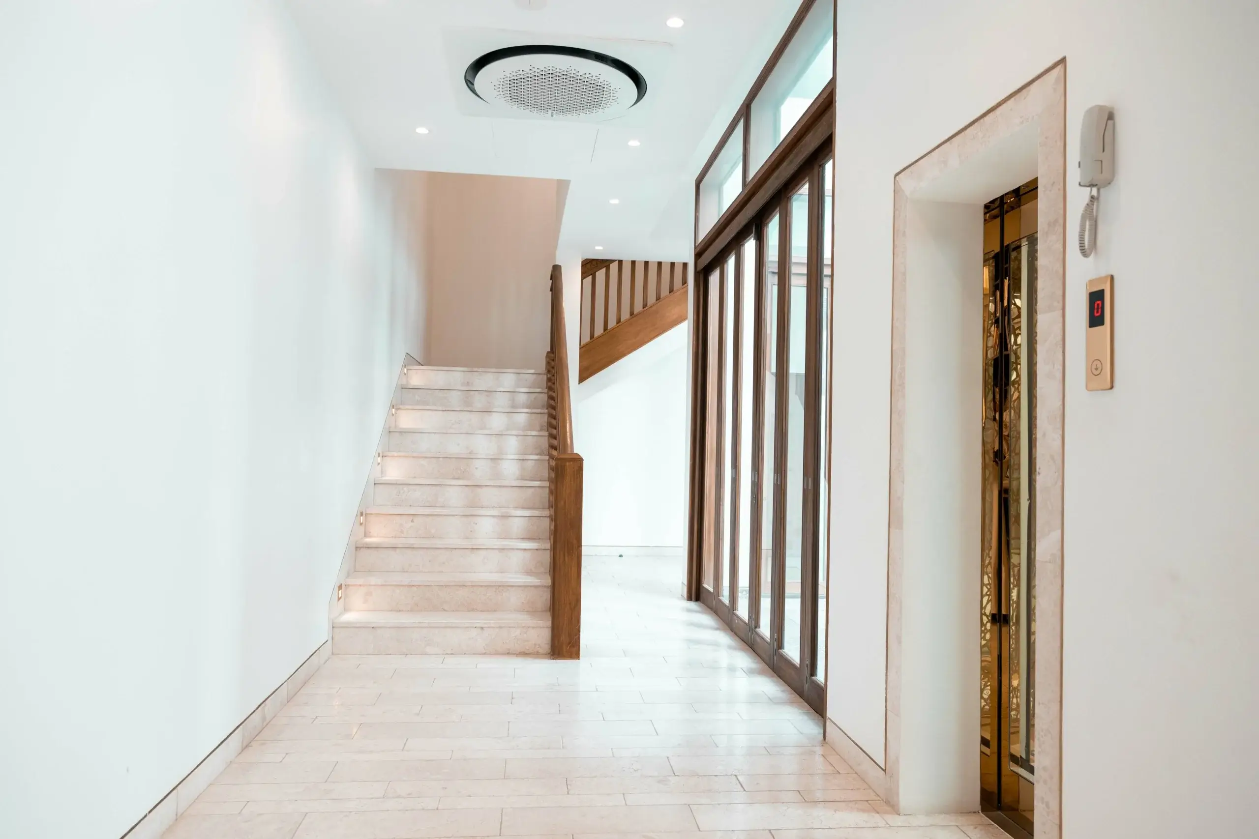 Elegant lobby with stairs, elevator, and white walls.