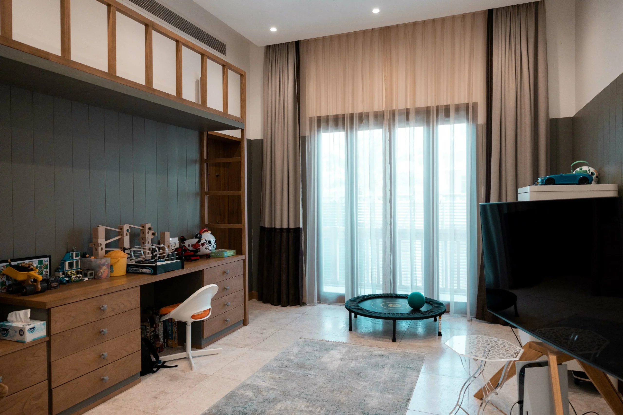 Kids' room with desk, toys, and trampoline.