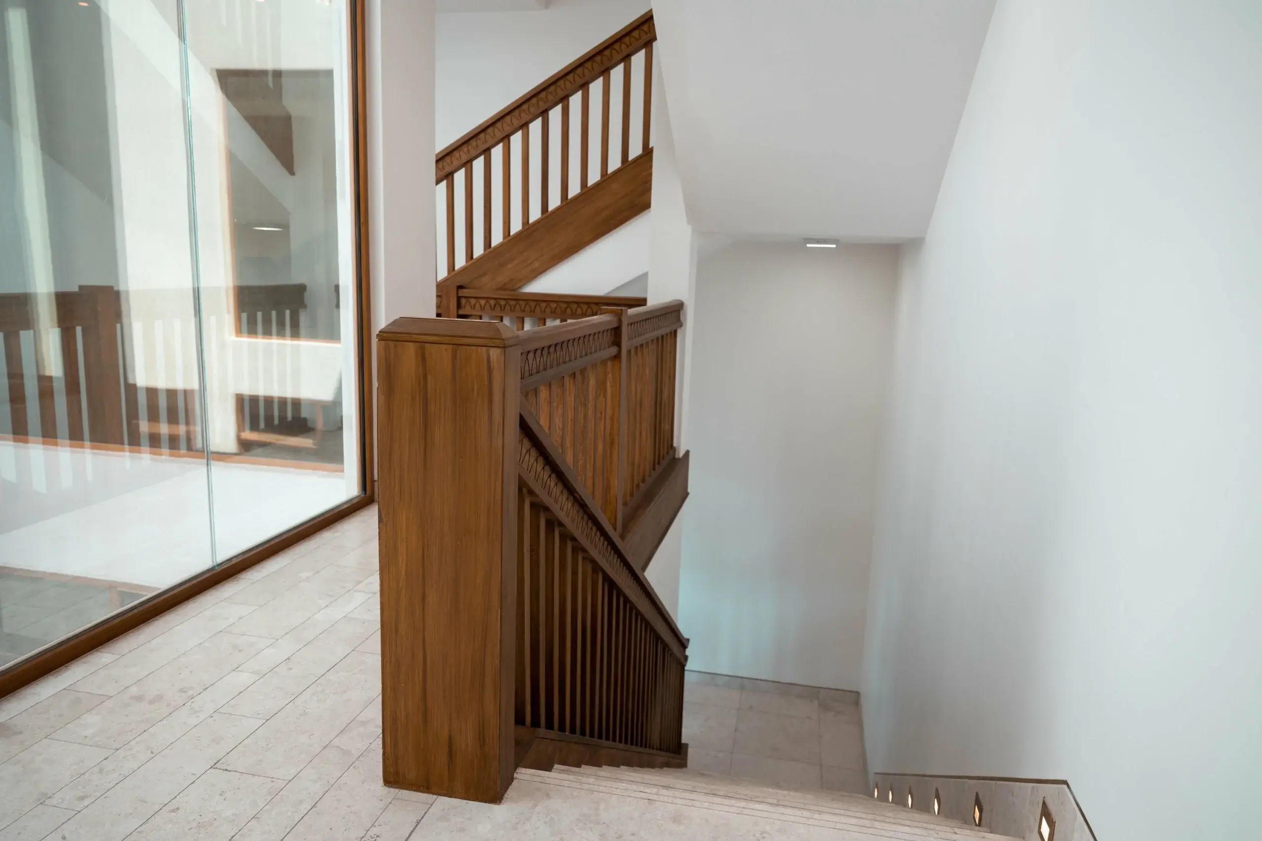 A wooden staircase with white walls