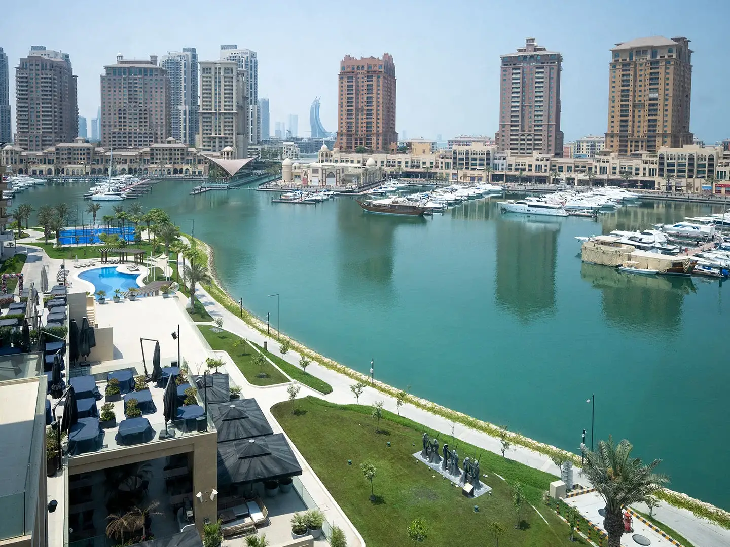 A bustling marina with yachts, buildings, and palm trees