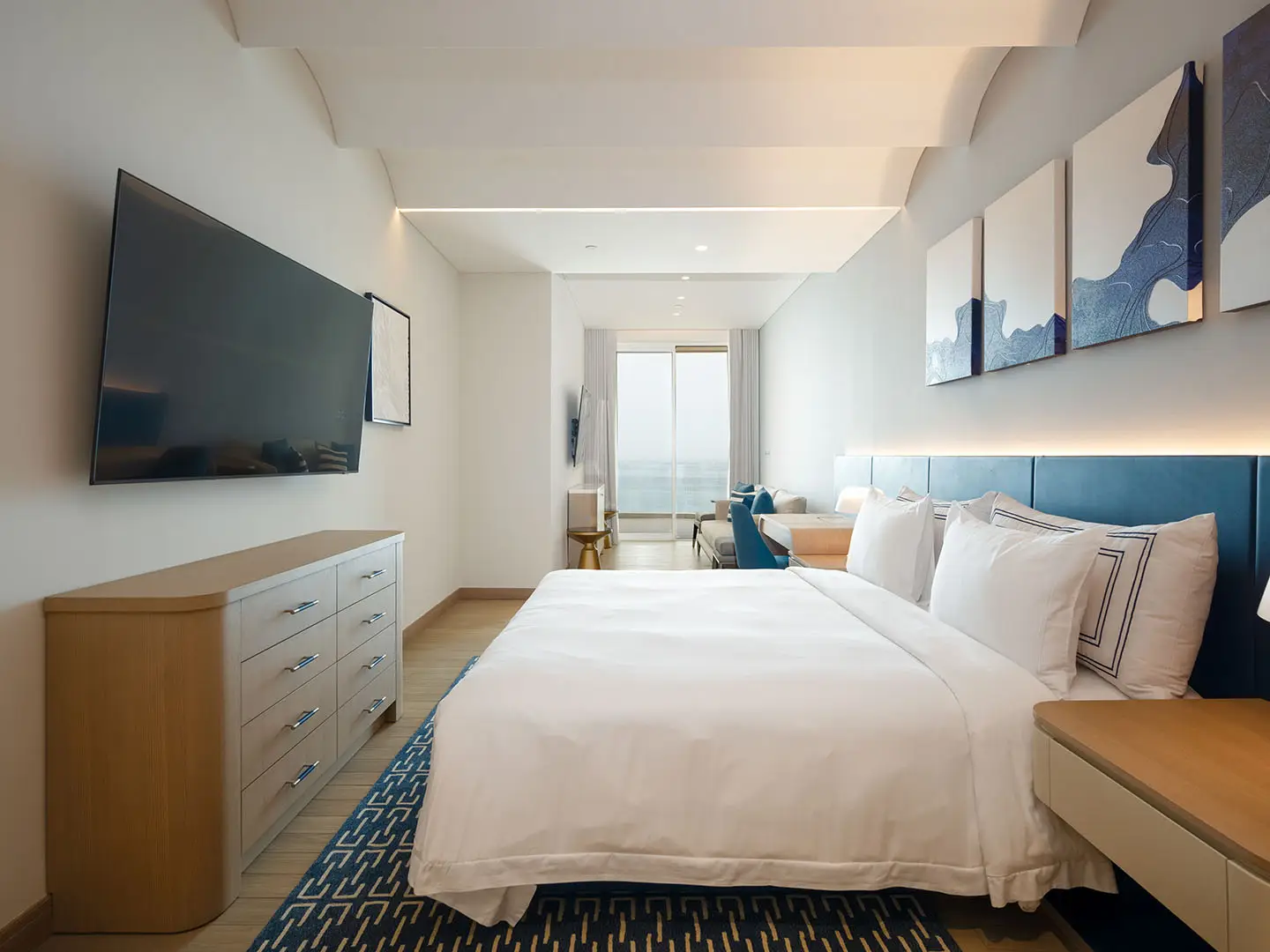 A clean, modern bedroom with a large bed and TV