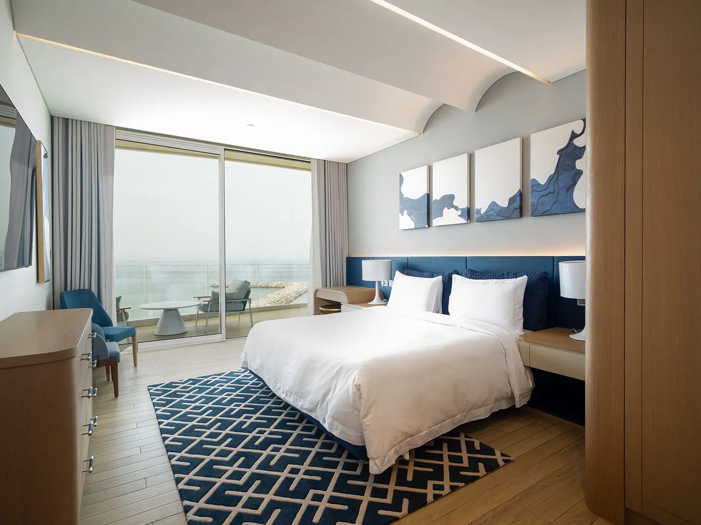 Bedroom with bed, blue rug, and sea view.