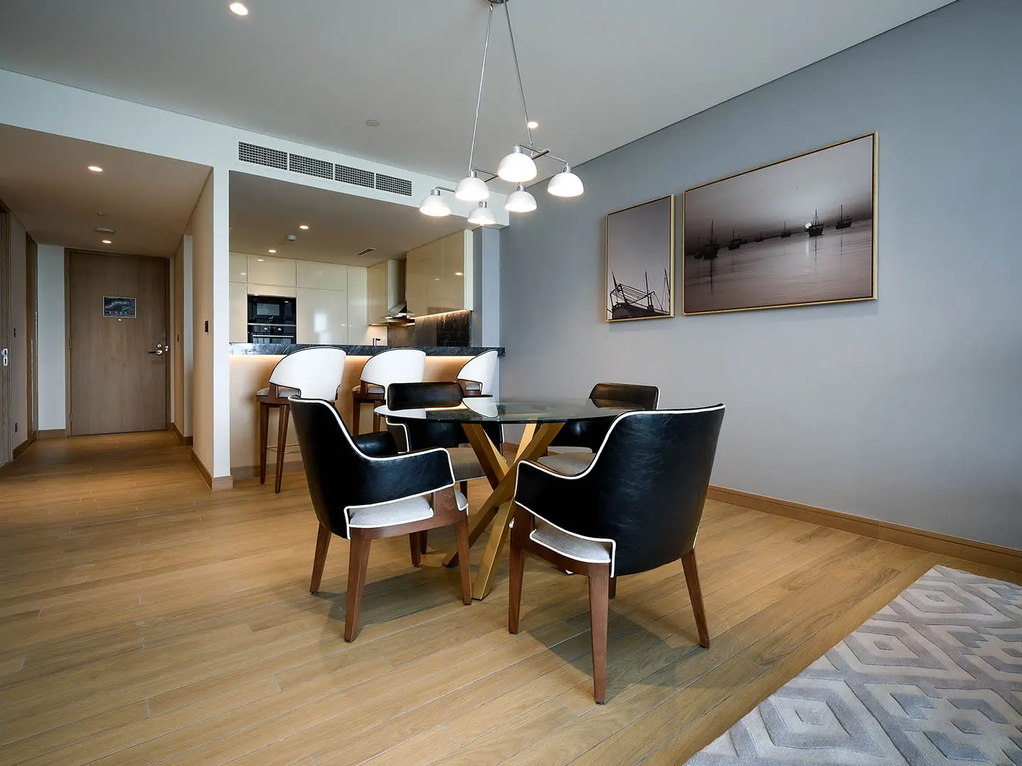 Dining room with black chairs and kitchen view.
