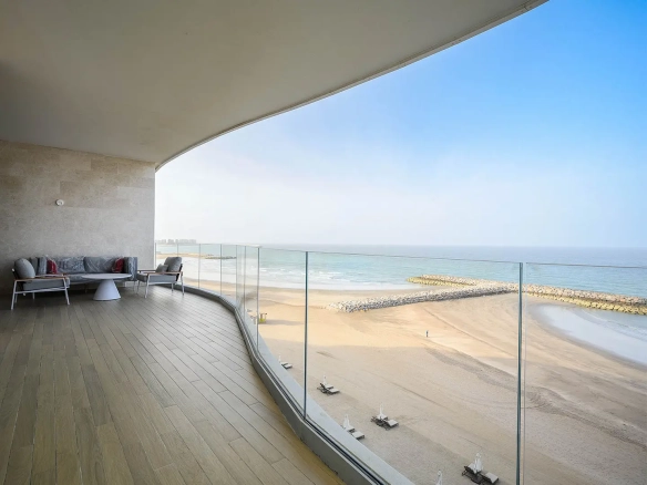A curved balcony overlooking a sunny beach.