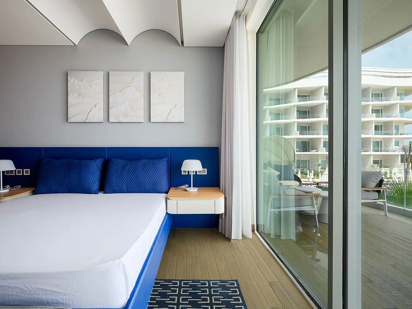 A bright bedroom with a blue bed and balcony
