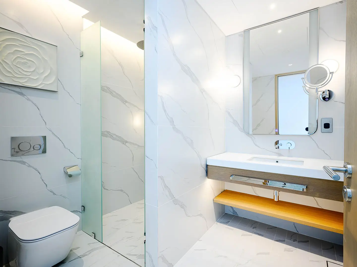 A sleek, white tiled bathroom with a floating vanity
