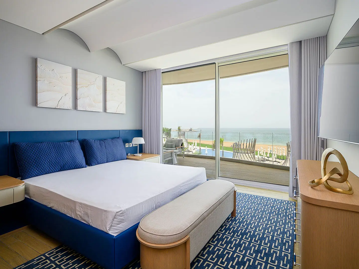 A blue and white bedroom with a sea view balcony.