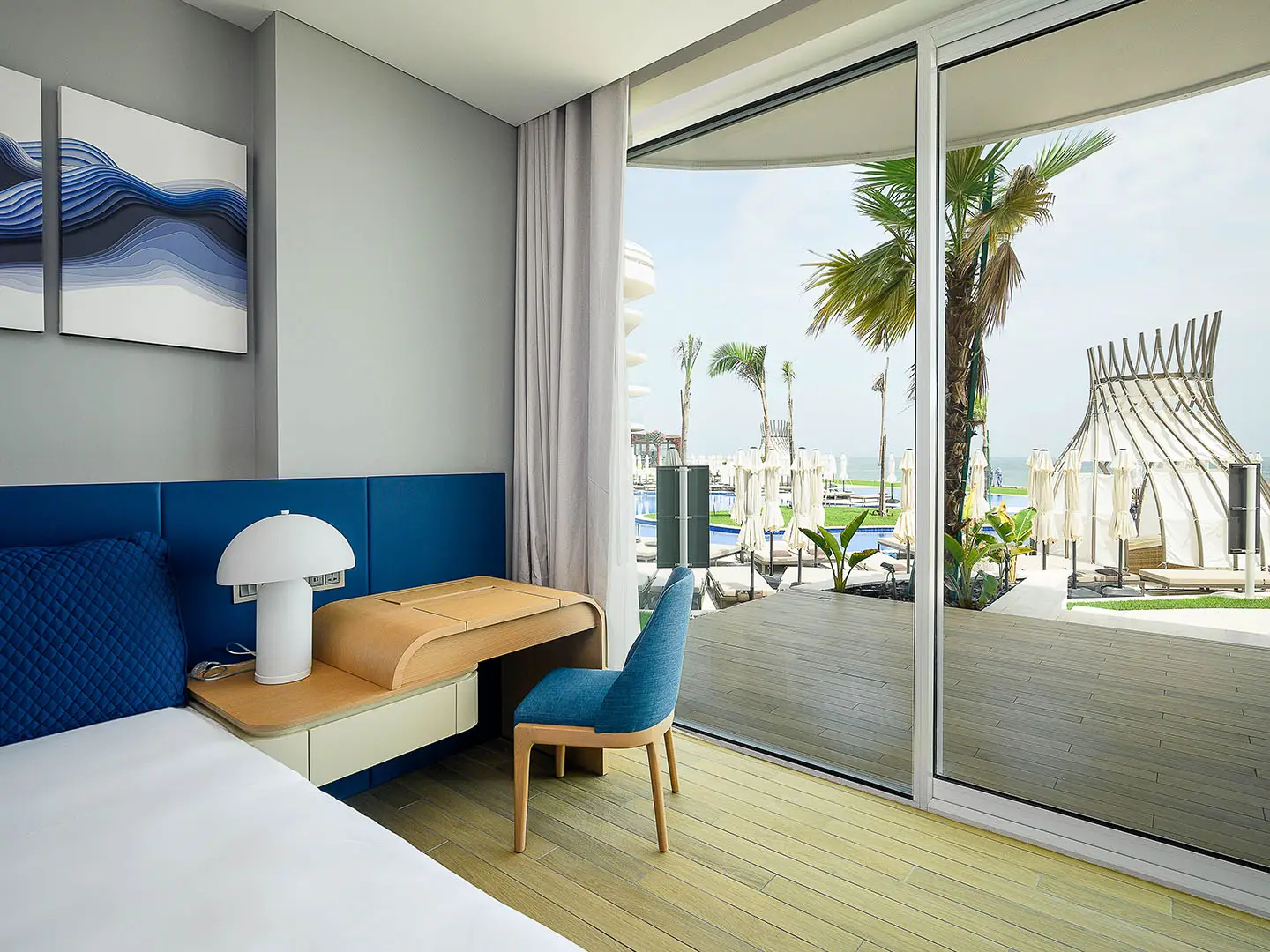 A modern bedroom with a desk, bed, and outdoor view