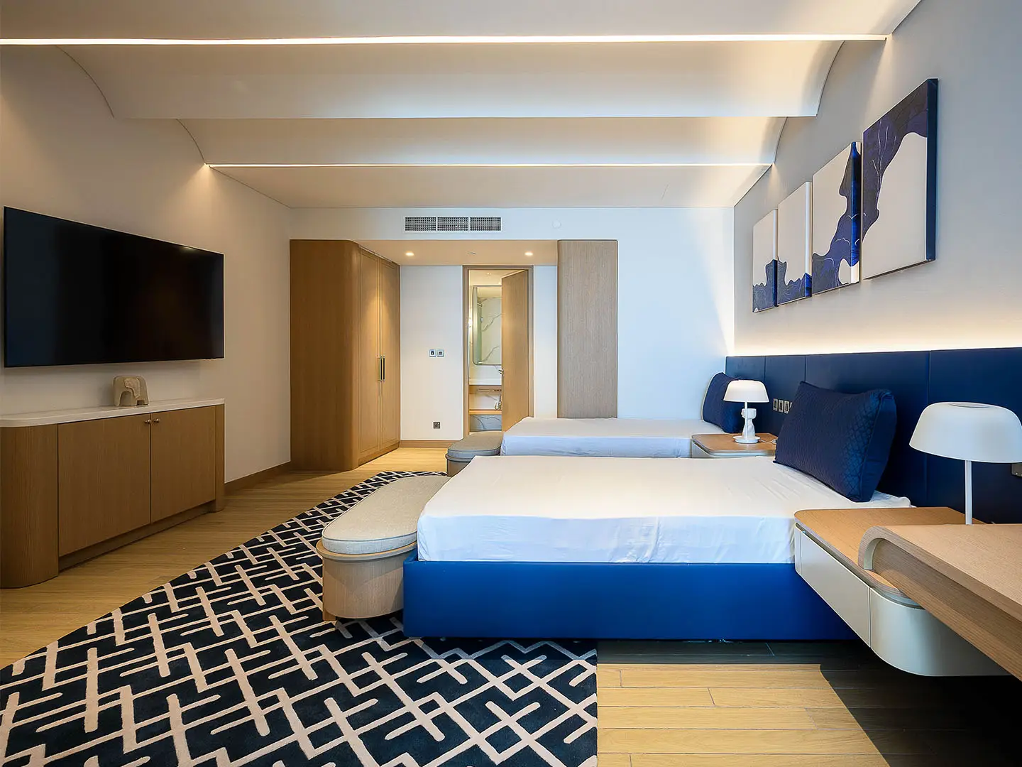 A hotel bedroom with two beds, a TV, and a rug
