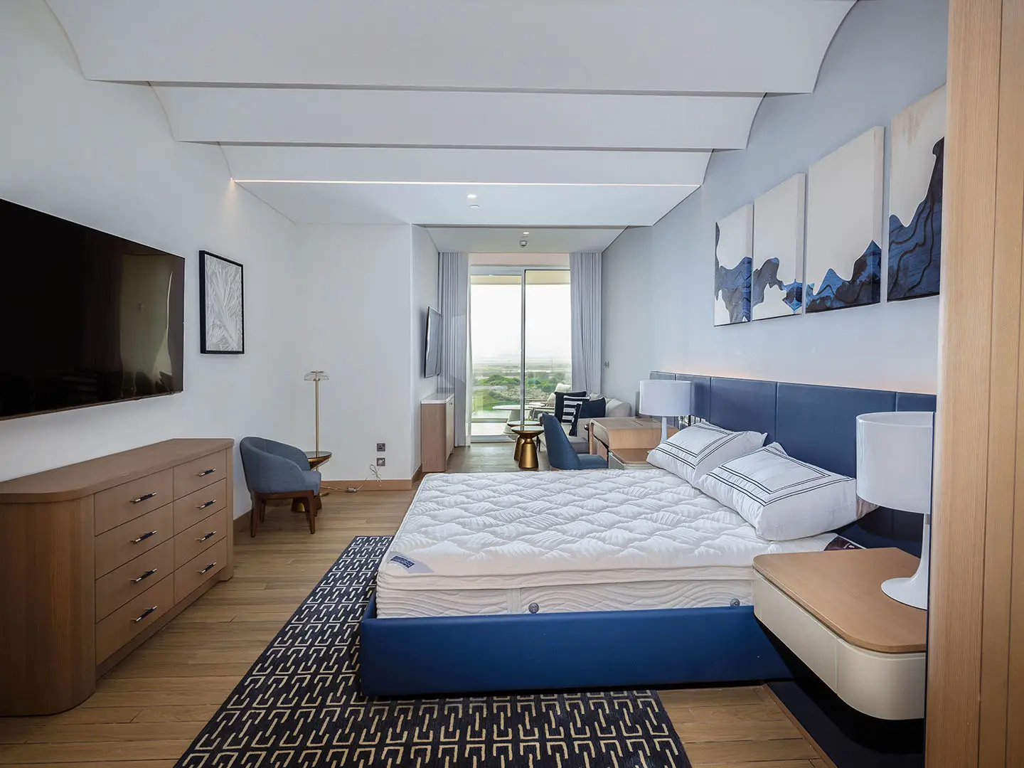 A spacious bedroom with a blue bed and TV