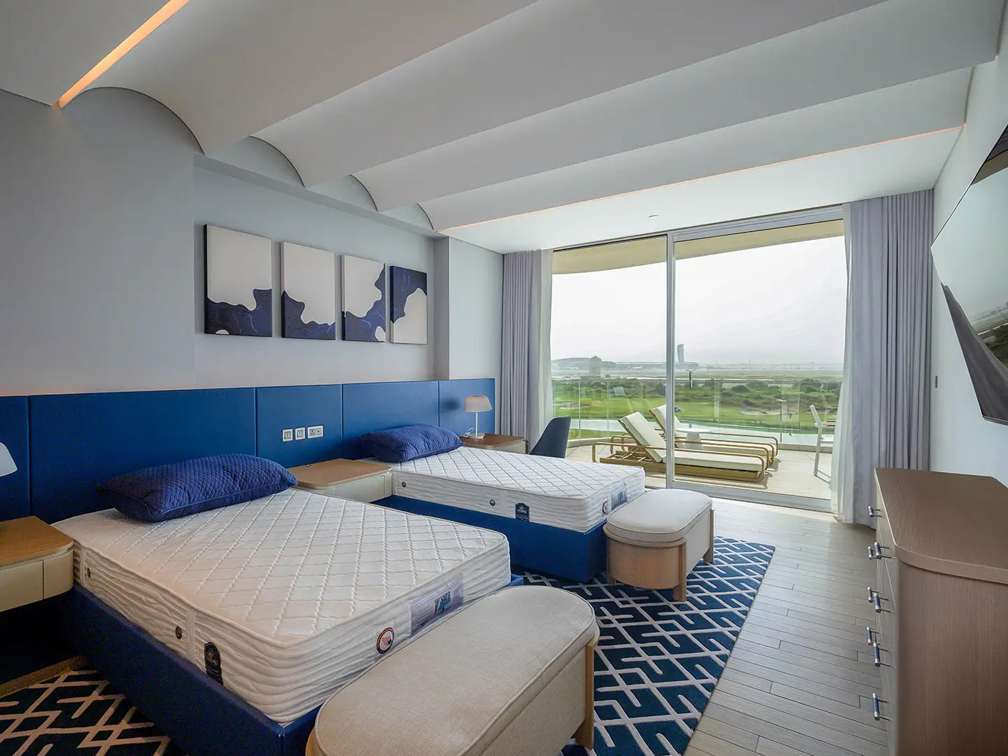 A bedroom with two beds, a rug, and a balcony view