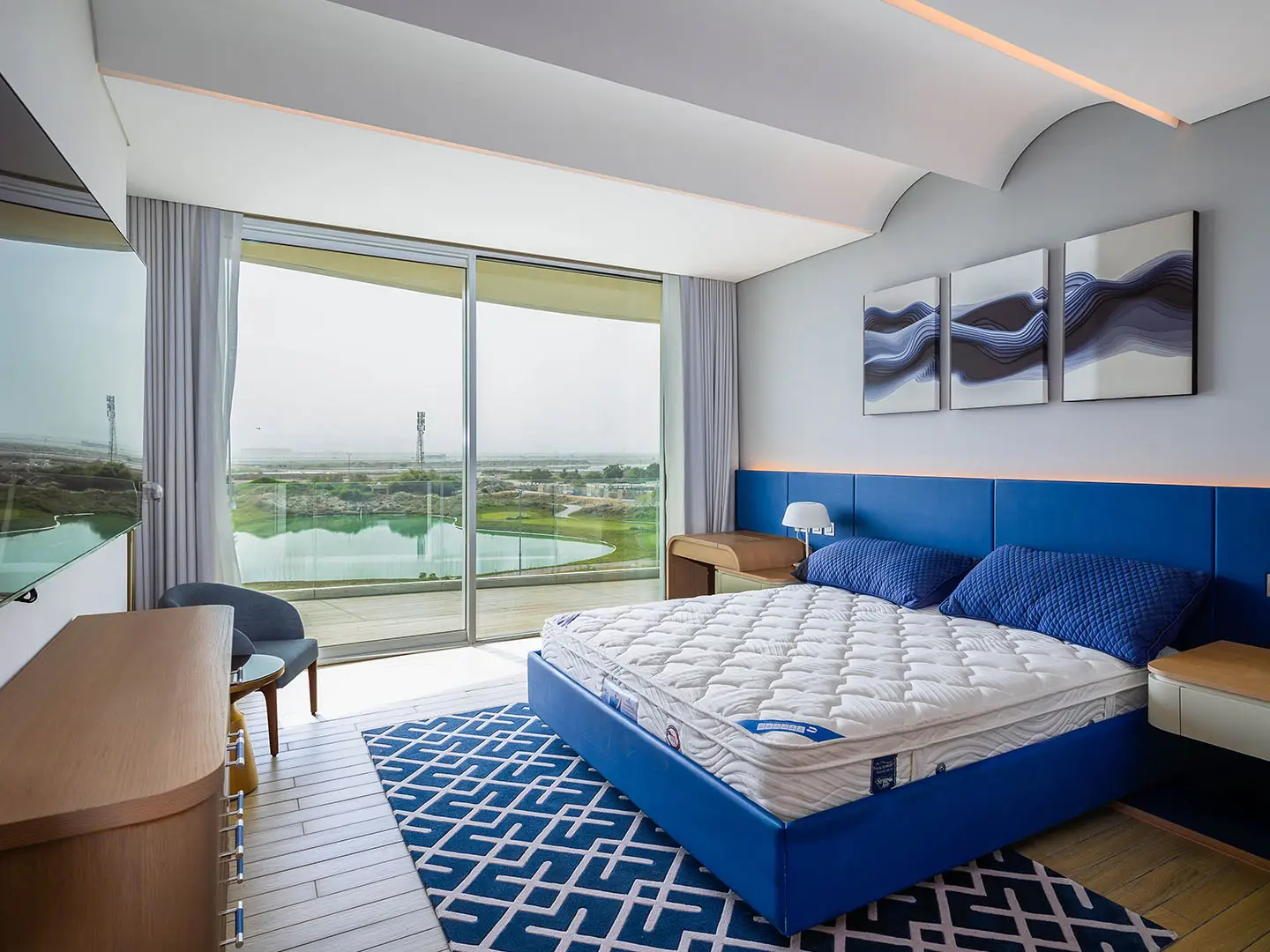 A spacious bedroom with a blue bed and balcony view