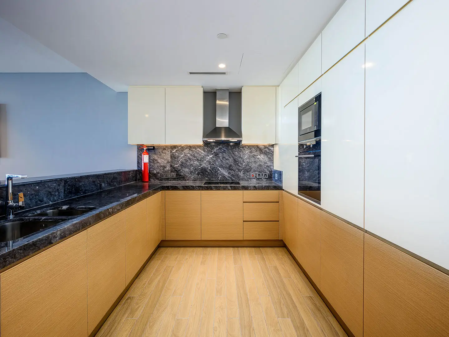 A modern kitchen with light wood cabinets and dark marble