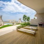 A luxury outdoor patio with lounges, a pool, and sea view