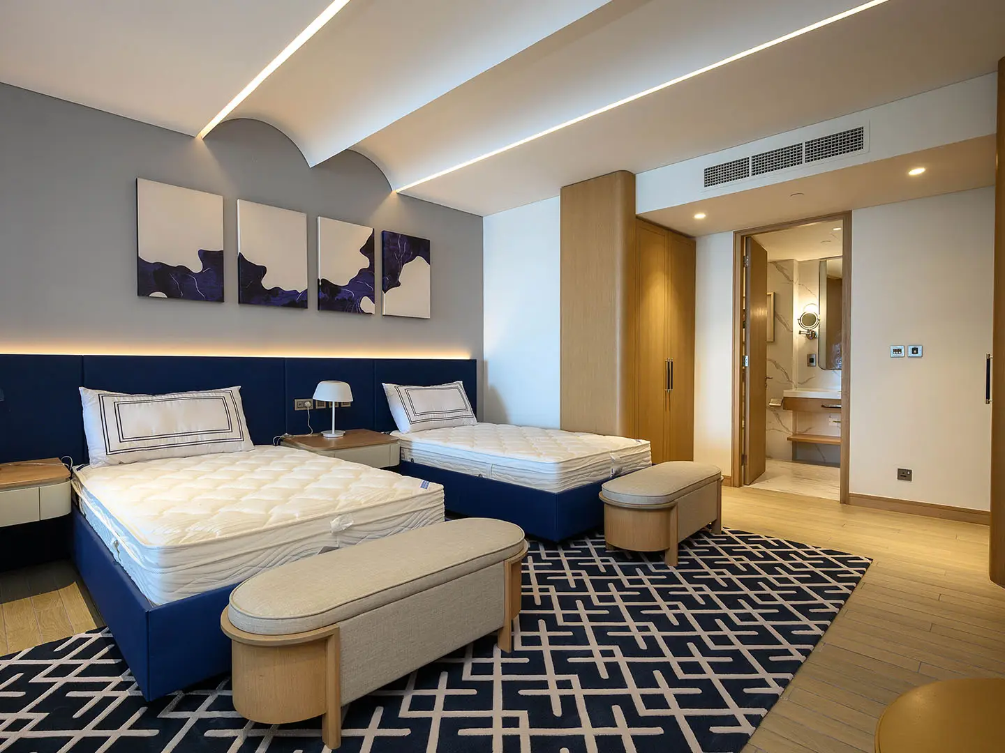 Elegant bedroom with two beds and modern bathroom