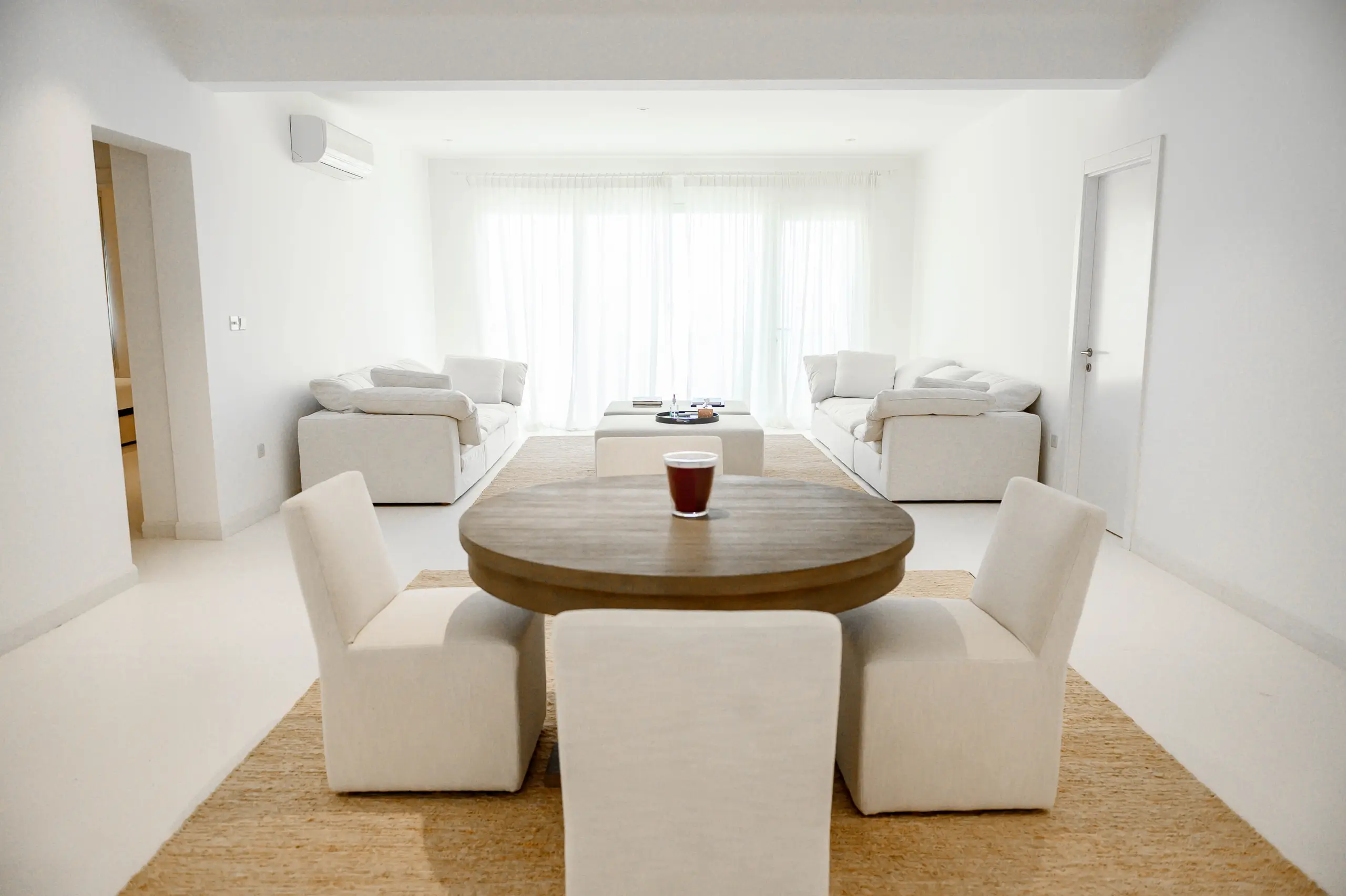 A minimalist white living room with a dining area