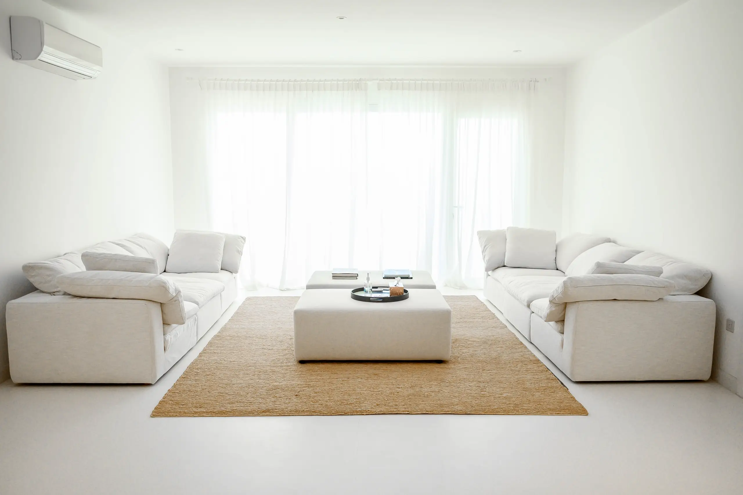 A bright, minimalist living room with white sofas.