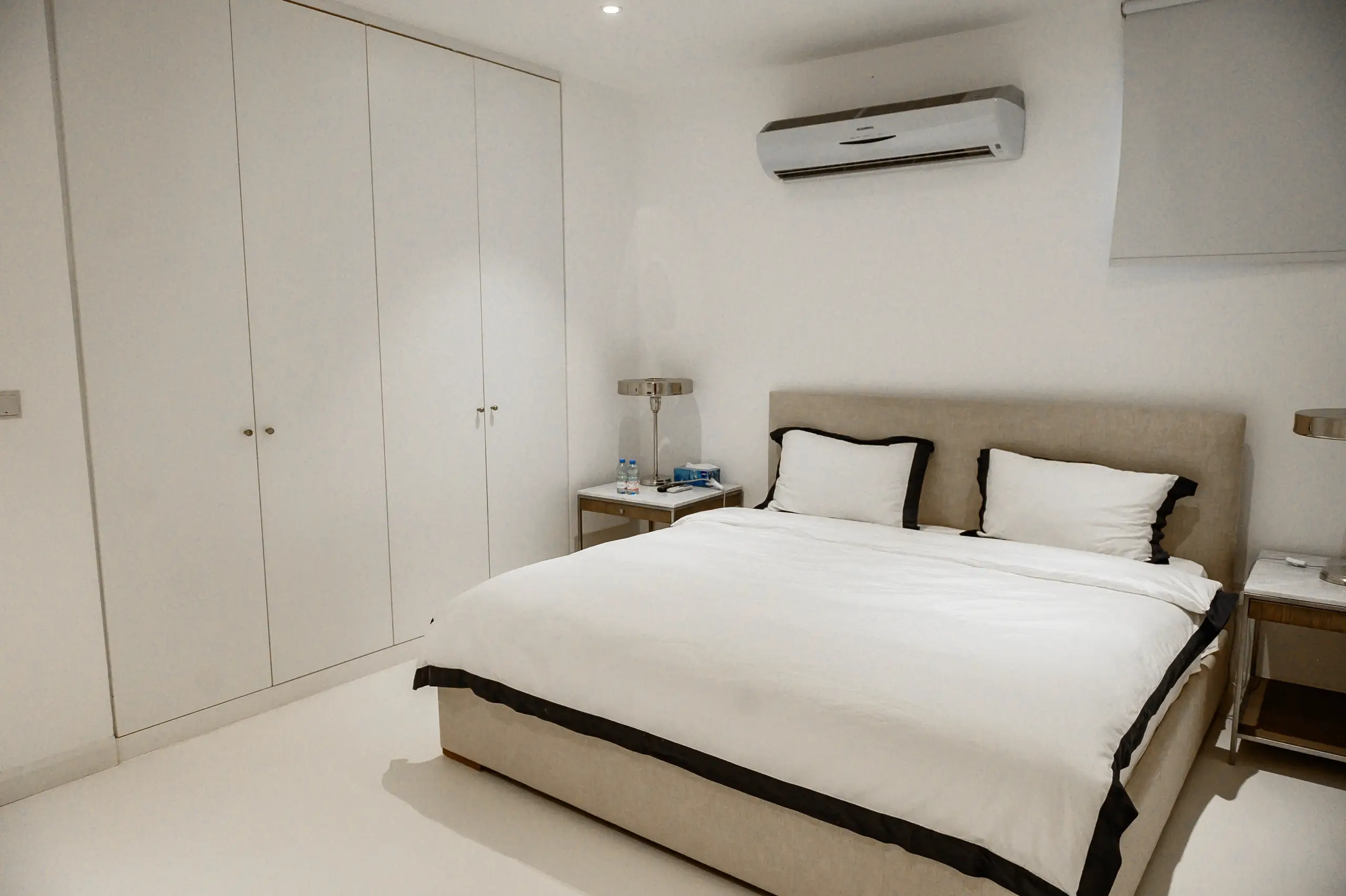 A white bedroom with a bed and wardrobe.