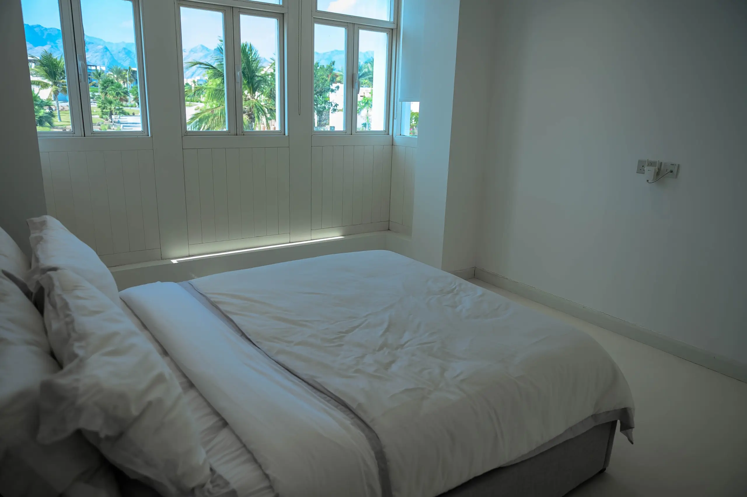 A minimalist bedroom with large windows.
