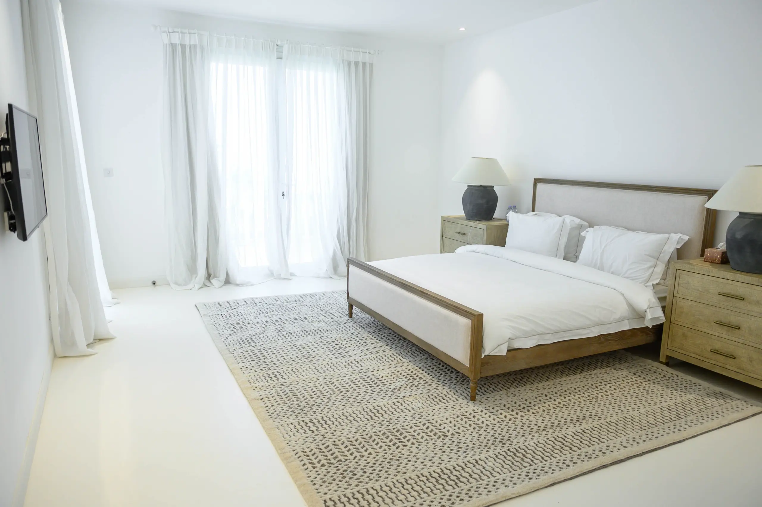 A minimalist white bedroom with a bed.