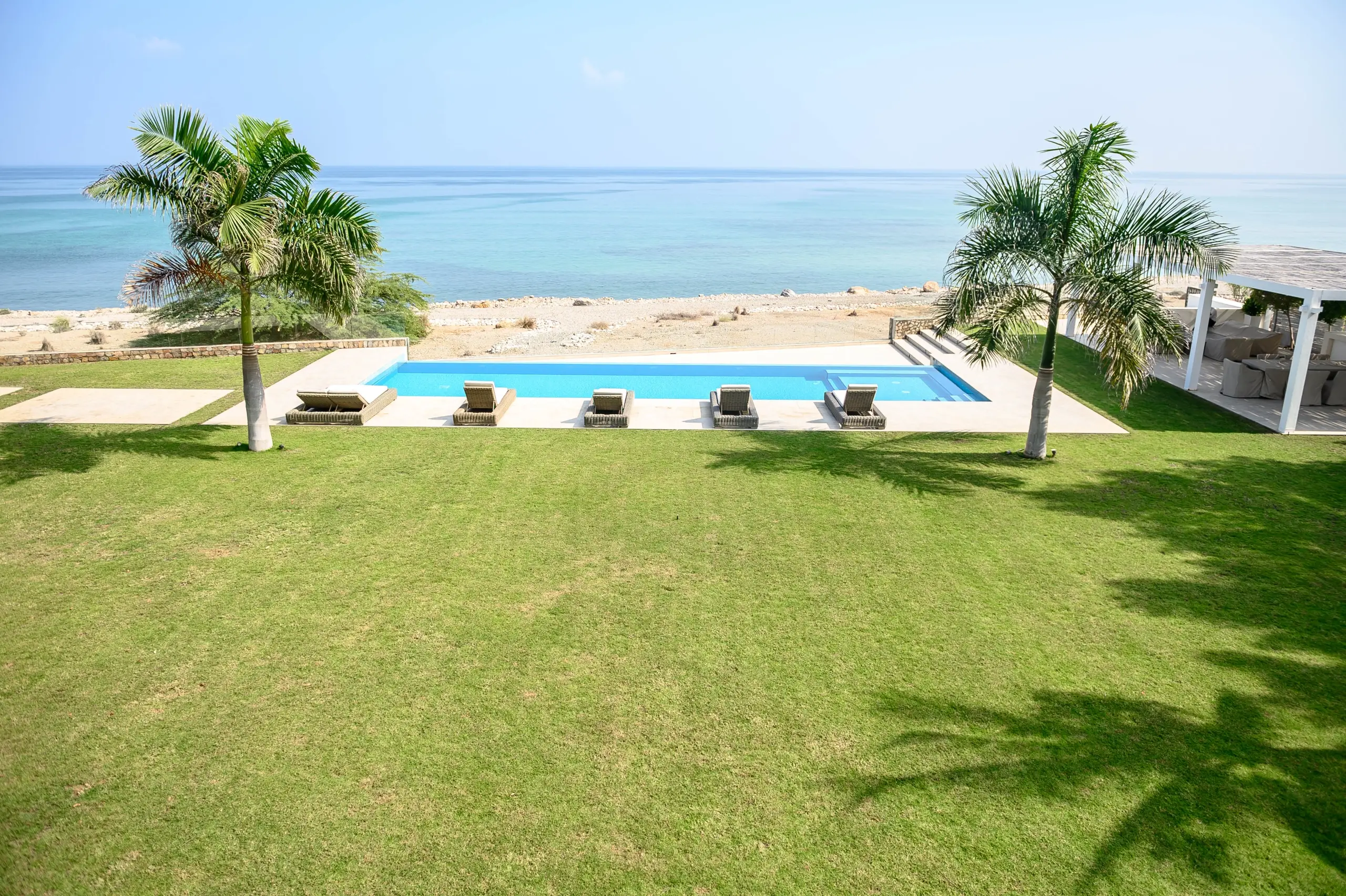 A luxurious beachfront property with a pool and lounge chairs