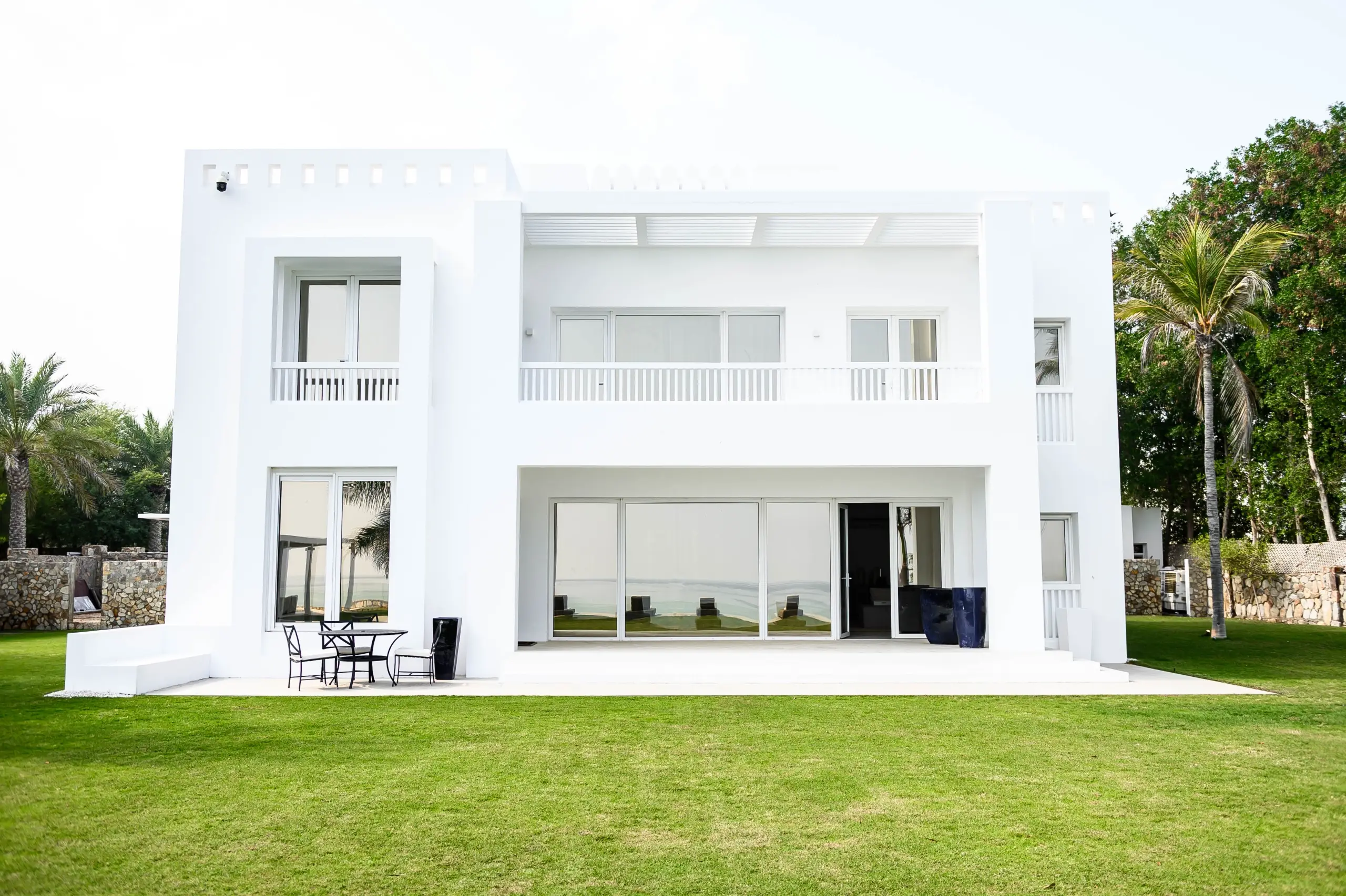 A modern white house with a green lawn.