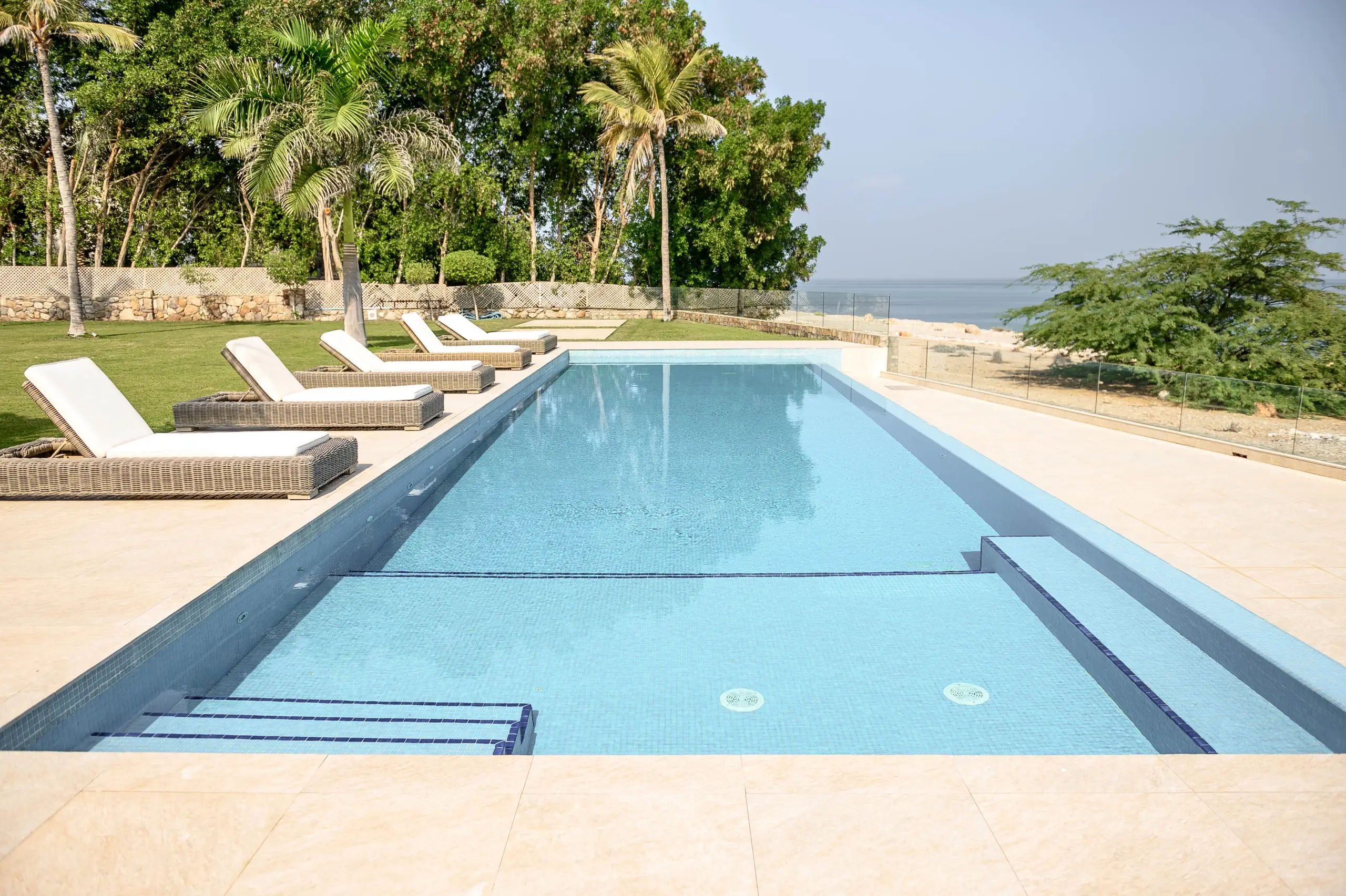 A large outdoor swimming pool with a distant sea view